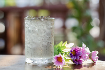 glass of water and fake flower on wood table