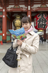 Fototapeta na wymiar ガイドブックを指差し東京観光をする若い女性　イメージ