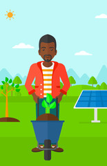 Man with plant and wheelbarrow.