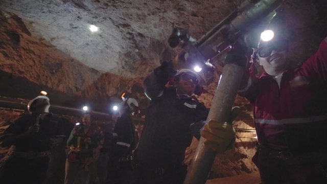 Workers in mine perforating the rock using a pneumatic drill