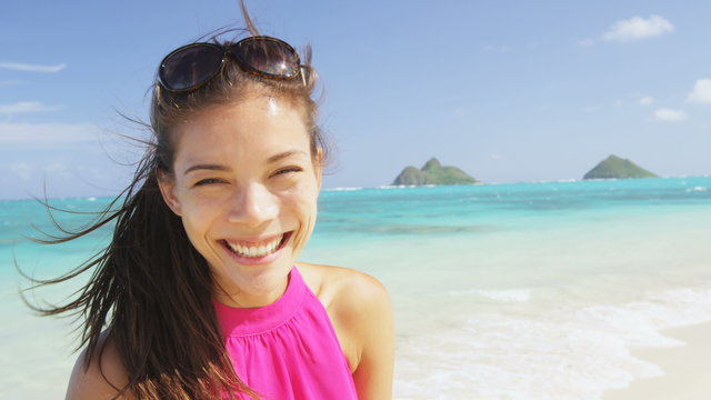 Woman portrait on beach. Multiracial model on Hawaii Lanikai beach. Young mixed race Asian Chinese / Caucasian female by ocean wearing pink sundress smiling looking at camera on summer travel holidays