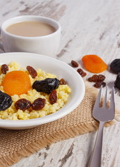 Cooked millet groats on white plate and cup of coffee with milk, healthy food and nutrition