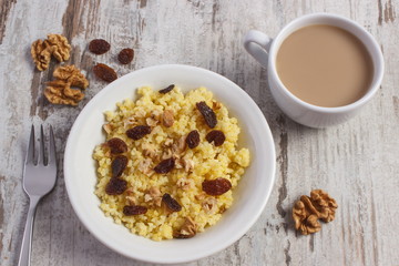 Cooked millet groats on white plate and cup of coffee with milk, healthy food and nutrition