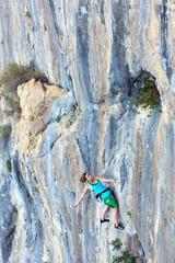 Young Female Climber assaulting vertical Rocky Wall
