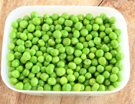 Cooked peas in a box on a wooden background.