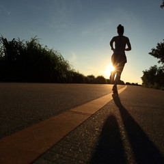 young fitness woman runner running on sunrise seaside road