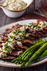 Steak with blue cheese sauce served with asparagus.