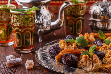 Naklejka na ściany i meble Moroccan mint tea in the traditional glasses with sweets.
