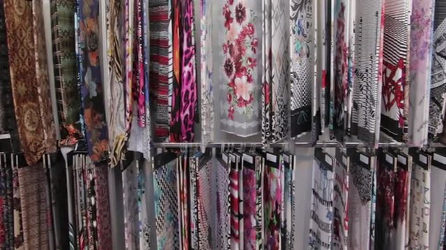 A variety of colorful fabric samples on display. Automated industrial sewing weaving knitting embroidery loom machine in textile cotton industry production fabric factory. Making clothes underwear.