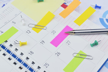 Pencil with sticky notes and pin on business diary page
