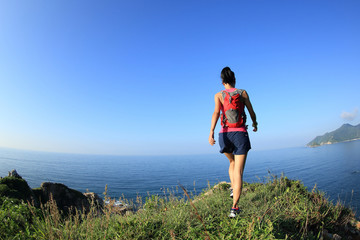 young woman hiker hiking on seaside mountain peak