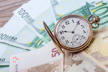 Time is money concept with euros and golden pocket watch.