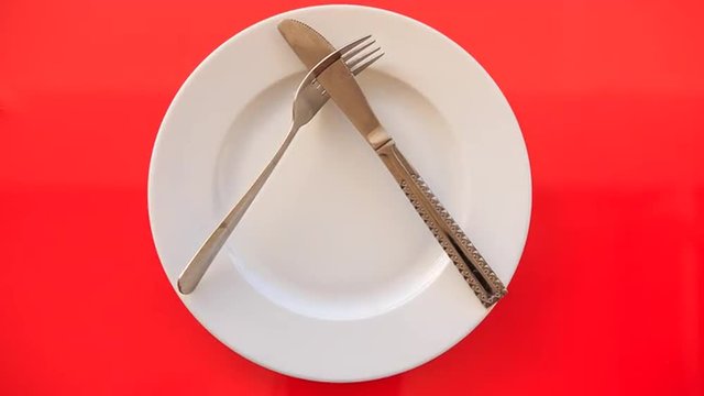 Hands Put Fork Knife at Acute Angle on Plate on Red Table