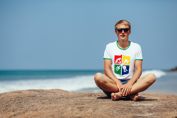  man sitting  on rock near the ocean