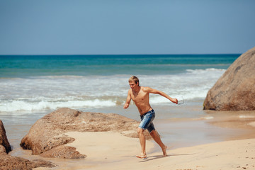 Man running on the beach with the sea in the background. Male ru