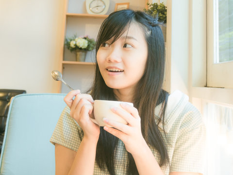 Asian beautiful young woman drinking coffee near window