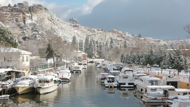 Boats and Yachts covered with snow parked on Goksu River creates very nice landscape with the hill and the trees, Istanbul