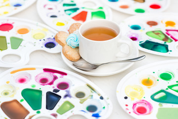 cup with tea and cookie surrounded watercolor palette