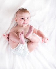 Baby in diaper on a white background with a branch of cotton
