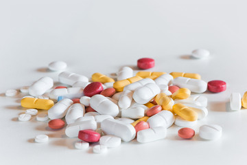 several different colored and sized medicine drug pills on white