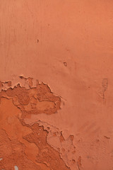 Old terracotta painted stucco wall with chipped paint. Backgroun