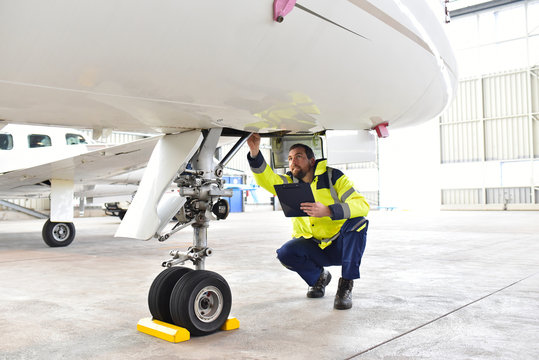 Mechaniker kontrolliert Fahrwerk eines Flugzeuges im Hangar // 
Mechanics controlled chassis of an airplane in the hangar