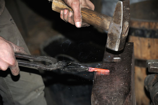Blacksmith forges a red-hot metal hammer