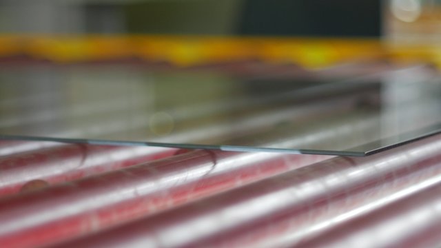 Glass is Moving By conveyor, Transporter to The Furnace for Tempering, Sheet of Transparent Glass Closeup