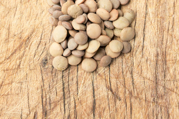 Uncooked lentils over wooden table close up.