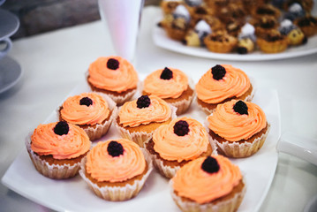 Delicious tasty dessert cupcakes with orange frosting, wedding r