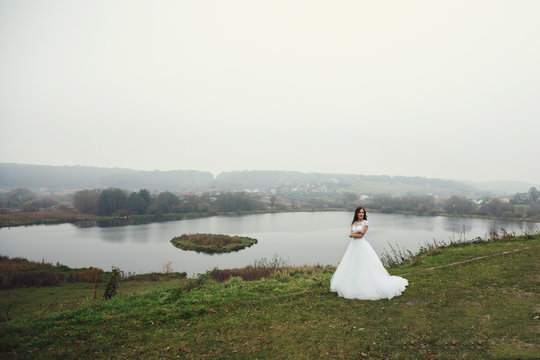 Beautiful romantic brunette bride princess posing near lake in a