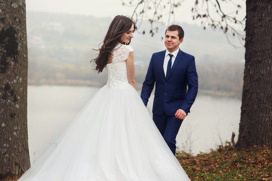 Happy beautiful couple of newlyweds posing near romantic lake