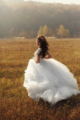 Beautiful happy brunette bride in white dress running in sunset
