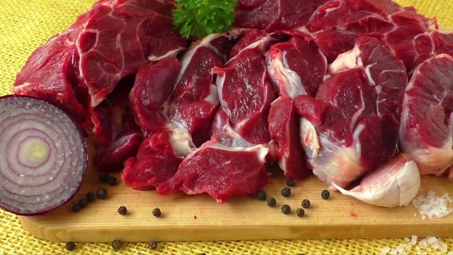 Raw beef on wooden board with garlic and onions
