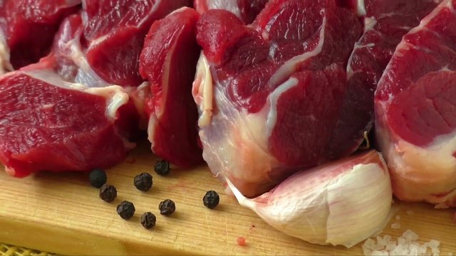 Raw beef on wooden board with garlic and onions
