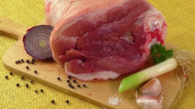 Raw knuckle of pork on wooden cutting board with garlic 
