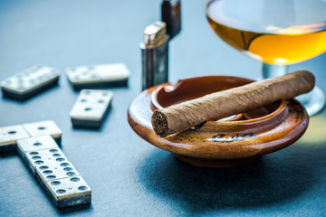 Cuban cigar in ashtray and domino game