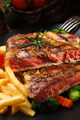 Grilled beef steak served with French fries and vegetables on a