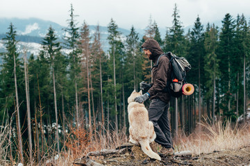 hiker with siberian husky dog looking at beautiful view in mountains