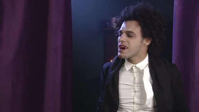 Vampire biting with fangs young man