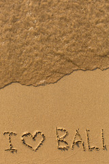 I Love Bali - text written on sandy beach with the soft wave.