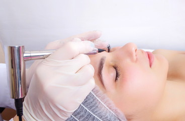 tattooist is using  gun tool for eyebrow permanent tattoo