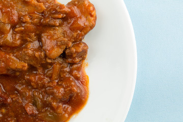 Braised beef on a plate atop a blue table cloth