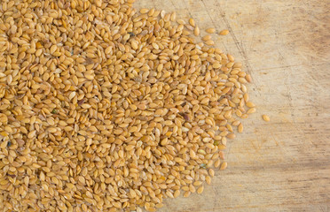 Portion of organic golden flaxseed spilled onto a wood cutting board