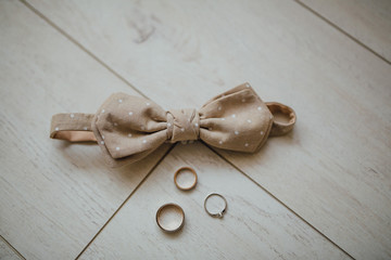 bowtie and wedding rings on a white wooden floor