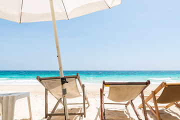 clear blue sea, blue sky and white sand with white umbrella and canvas beds on paradise island in Thailand