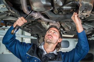 Mechanic repairing a lifted car wit