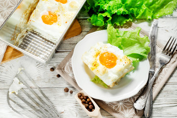 
breakfast or lunch , air , beaten egg and baked in the oven , with lettuce and herbs on a white wooden background