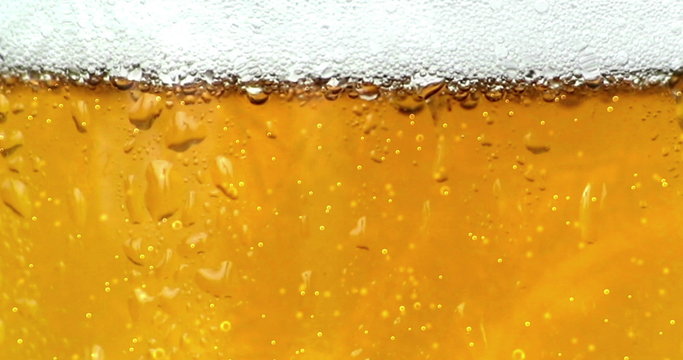 bubbles movement inside a glass of beer with drops and foam as background seamless loop