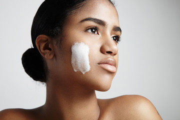 woman with a foam on a cheek. Cleansing skin concept